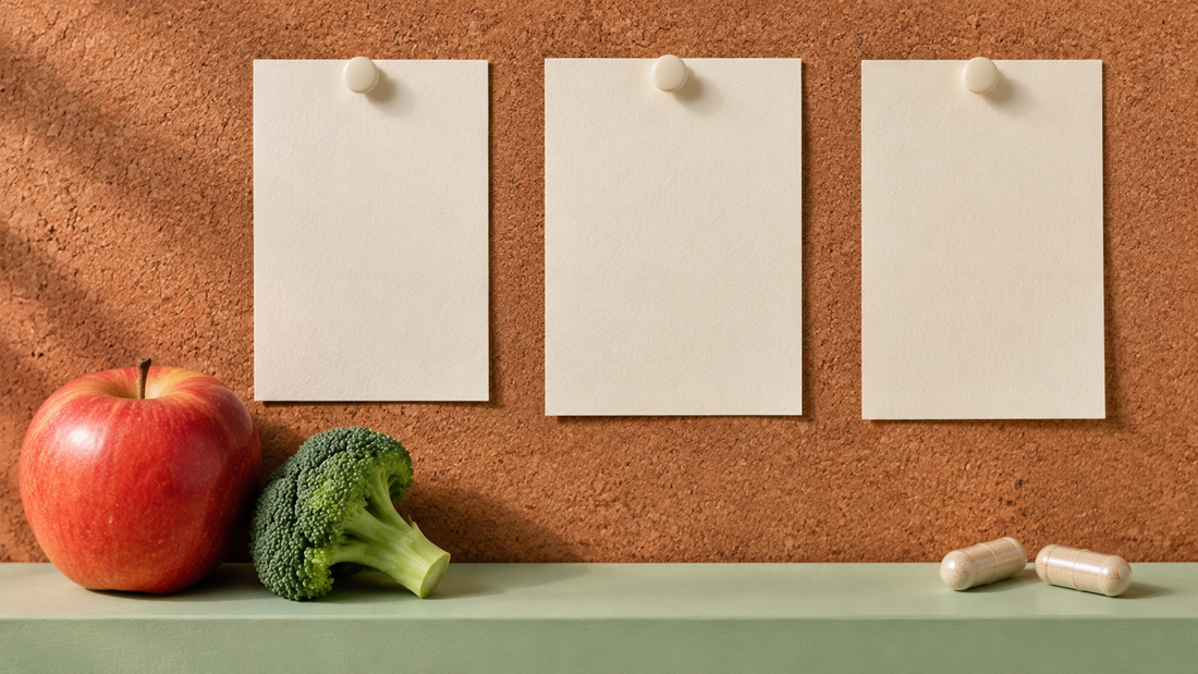 Illustrative blank cards on a cork board above an apple, broccoli and generic capsules.