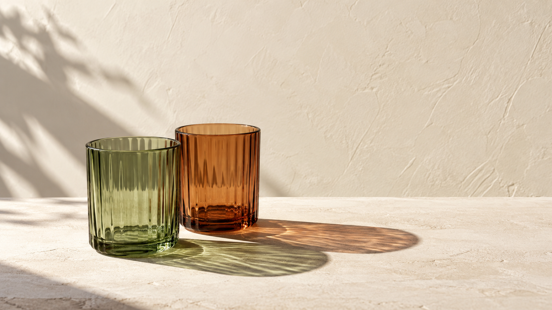 Illustrative sage and rust glass tumblers whose shadows overlap on a cream plaster surface.